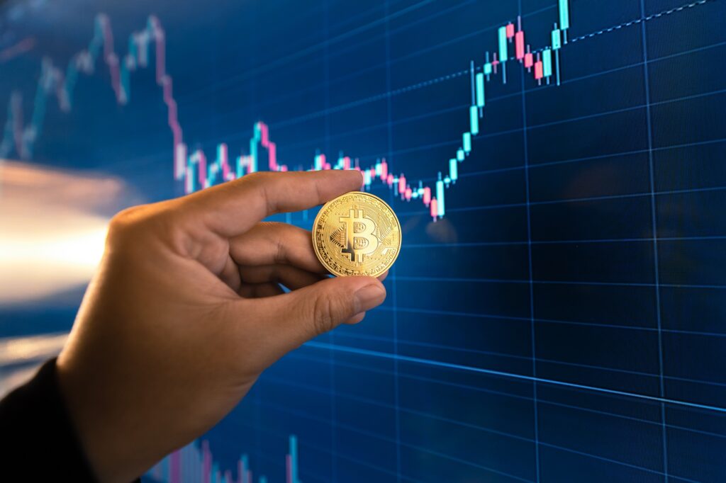 Bitcoin coins in hand in front of the computer